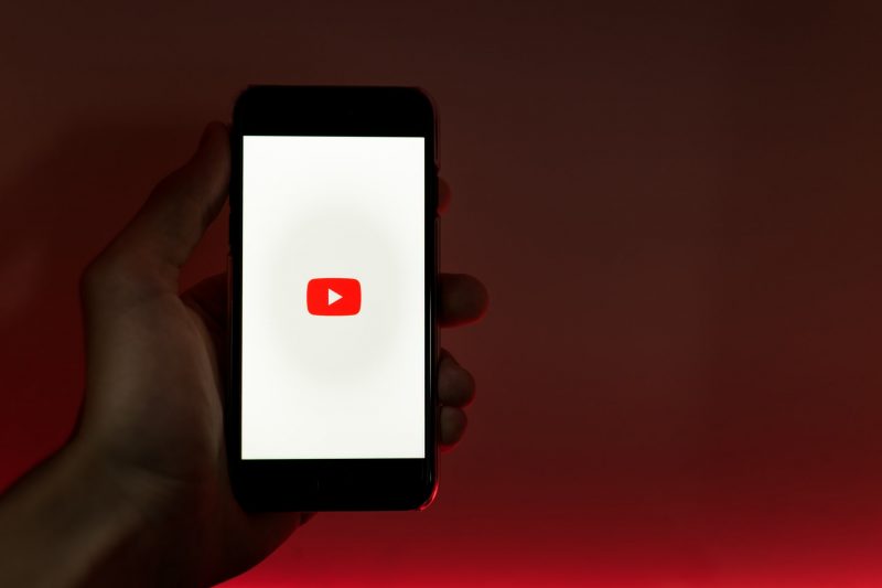 Person holding smartphone with YouTube App
